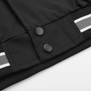 Detailed macro view of matte black snap buttons and striped ribbed hem on a baseball jacket