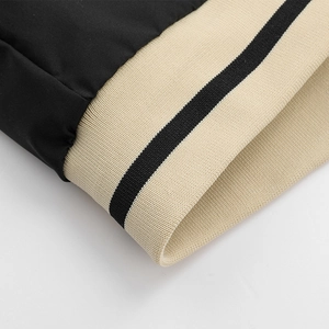 Close-up of black casual jacket with beige ribbed knit cuffs and black stripe detail