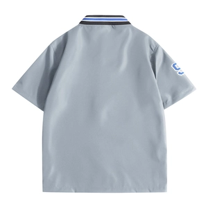 Men's light grey polo shirt with striped collar and decorative number nine sleeve patch