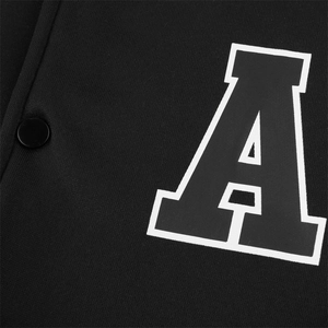 Macro shot of white letter A embroidery and black metallic snap button on knit jacket