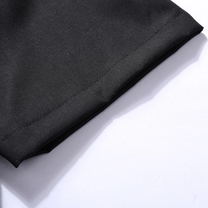 Detailed close-up showing precise flat stitching on the black polo shirt hem and fabric