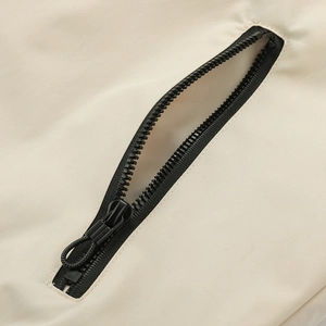 Detail shot of black zipper pocket with cord puller on beige casual sports jacket