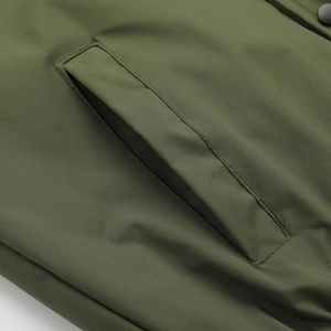 Detailed view of army green jacket pocket with high-quality stitching and metal snap button