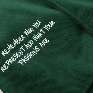 Detail of forest green baseball jacket with white printed slogan and premium knit texture