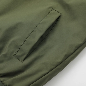 Detailed view of olive green jacket fabric showing reinforced slanted pocket and fine stitching