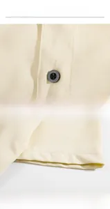 Detailed macro view showing black button and neat cuff on ice silk beige shirt
