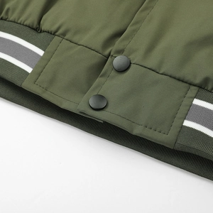 Detail of army green jacket with striped ribbed hem and black metal snap buttons