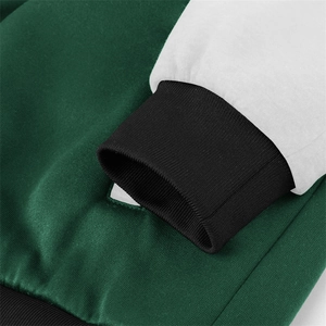 Detailed view of the dark green knit jacket with white sleeves and ribbed cuffs
