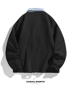 Detail der schwarzen Cordjacke mit blauem Denim-Kragen und weißem Kordelzug am Saum
