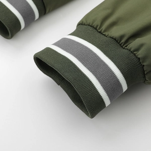 Close-up of olive green jacket cuff featuring grey and white striped ribbed knit details