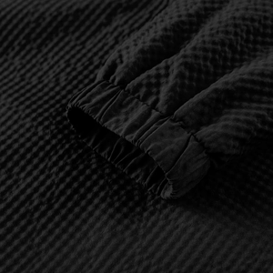Close-up of elastic ribbed cuff on black hooded jacket with waffle texture fabric