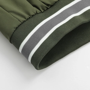 Detail of army green jacket featuring grey and white striped ribbed cuffs and hem