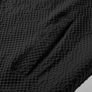 Close-up of black waffle textured fabric showing fine stitching on pocket detail