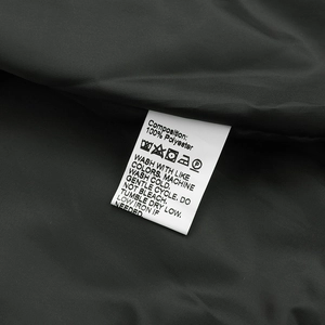 Detail view showing 100% polyester material composition label on black baseball jacket