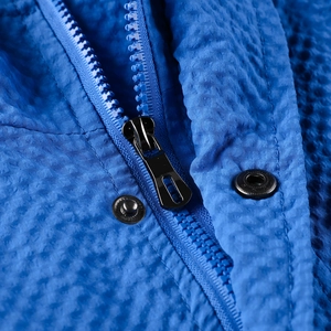 Detail of blue textured fabric on hoodie with black zipper and metallic snap button