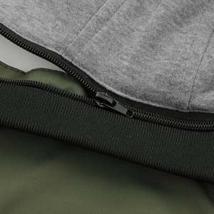 Detail of metal zipper and multi-fabric stitching on olive green hooded baseball jacket