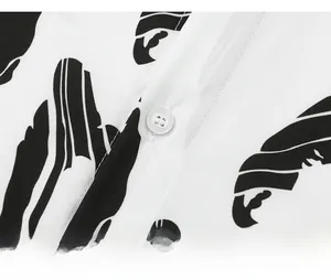 Detail shot of a white Hawaiian shirt featuring abstract black print and neat buttoning