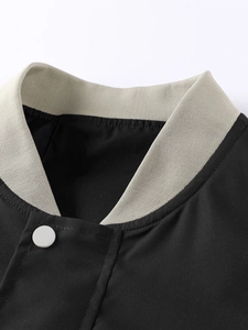 Detail of the grey ribbed collar and white snap button on a black and grey sporty jacket