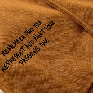 Macro detail of ginger knit hoodie featuring inspirational black slogan print text