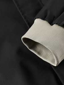 Close-up of black jacket cuff with khaki ribbed knit detailing and elastic texture