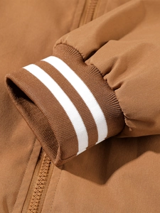 Close-up of brown jacket cuff with classic white double-stripe knitted ribbed design