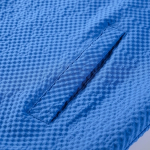 Macro detail of royal blue hooded jacket fabric with 3D waffle texture and pocket seam