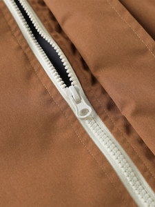 Detail of white plastic zipper on brown fabric of a lightweight casual jacket for men