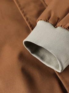 Close-up of windproof fabric texture and elastic ribbed cuffs on a brown casual jacket