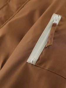 Macro shot of brown jacket fabric featuring a white resin zipper and durable stitching
