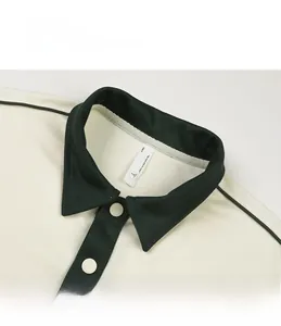Détail du col polo contrasté avec deux boutons et étiquette de taille sur tissu crème uni