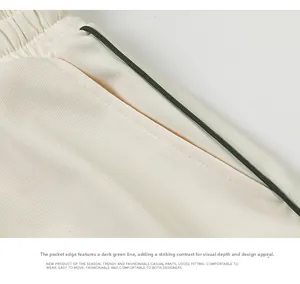 Détail du pantalon décontracté crème avec coutures contrastées vertes à la taille