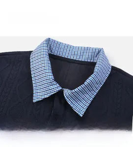 Detail of navy cable knit sweatshirt featuring a blue and white plaid polo collar