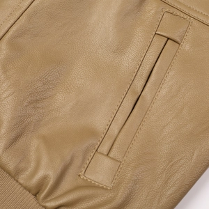 Détail de veste en cuir camel montrant le grain, la poche et l'ourlet côtelé