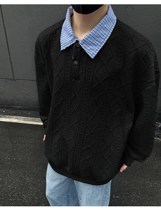 Close-up of black cable-knit sweater with a plaid collar detail and textured knit pattern