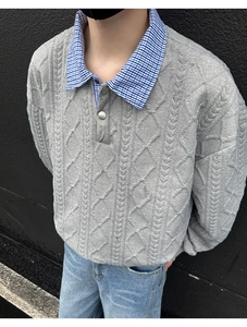 Detail of grey cable knit sweater featuring a blue plaid collar and metal button accents