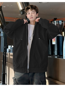 Detail view of large cargo pockets and silver zipper on black oversized outdoor jacket