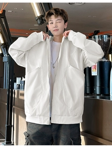 Detail of white oversized outdoor jacket featuring large pockets and silver zipper closure
