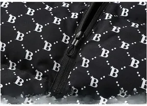 Detailed close-up of smooth black metal zipper with letter B patterned fabric on the jacket