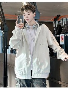 Close-up of cream hooded outdoor jacket with oversized pockets and utility arm pocket