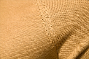 Macro view of camel knit sweater showing detailed cable stitch texture and fabric quality