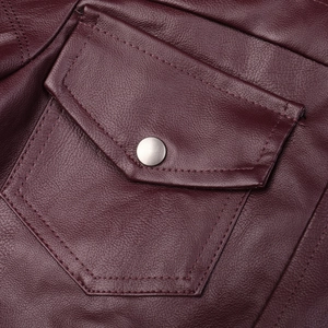 Détail macro de la veste en cuir bordeaux montrant la poche à rabat et le bouton