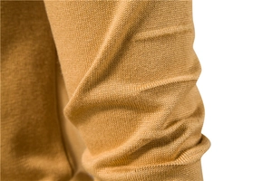 Macro shot showing the ginger yellow knitted sweater fabric texture and ribbed cuff detail