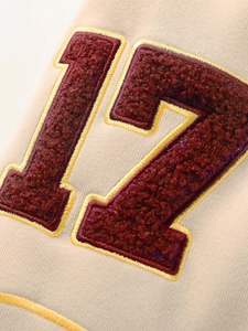 Détail de la broderie bouclée bordeaux numéro 17 sur le tissu d'un blouson de baseball