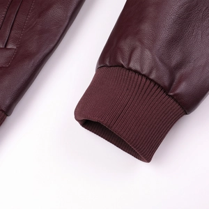 Détail d'une veste en cuir bordeaux avec poignets en tricot côtelé et coutures précises