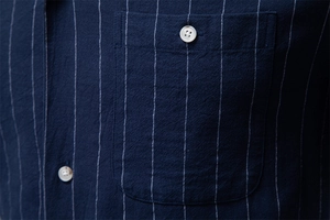 Détail d'une chemise rayée en coton bleu marine avec poche de poitrine et boutons