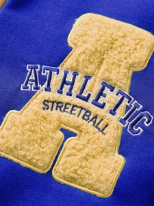 Détail macro de la broderie bouclée avec lettre A jaune sur tissu bleu marine de sport