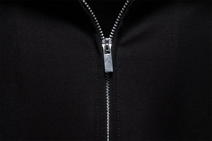 Close-up detail of silver metal zipper and premium knit texture on black business polo shirt