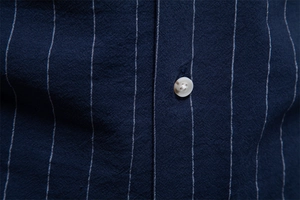 Vue macro du tissu en coton à rayures bleu marine avec détail de bouton sur chemise homme