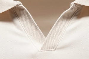 Macro shot of cream Tencel Polo shirt collar showing detailed pique knit and ribbed texture