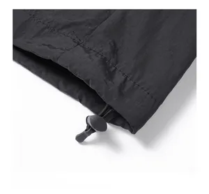Detailed close-up of adjustable elastic drawstring and toggles on black nylon jacket hem